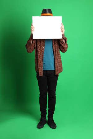 The senior Asian man dressing in Thanksgiving season color theme, wearing orange plaid shirt and black hat standing on the green background.の写真素材