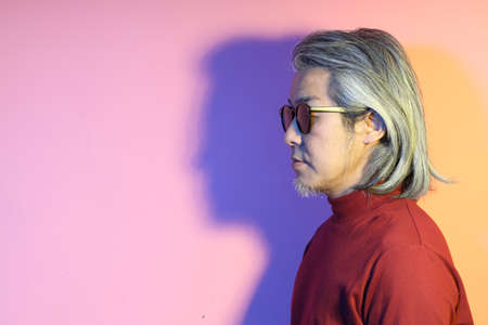 The cool senior Asian man in the gel color light photography.