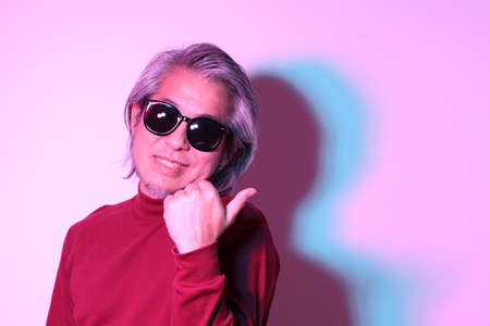 The cool senior Asian man in the gel color light photography.の写真素材