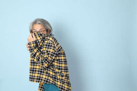 The senior Asian man with yellow plaid shirt standing on the blue background.の写真素材