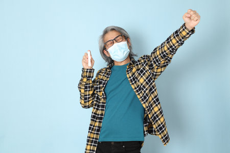 The senior Asian man with yellow plaid shirt standing on the blue background.の写真素材