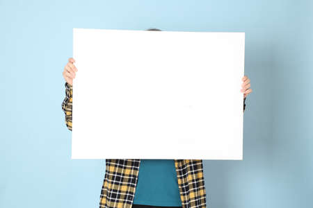 The senior Asian man with yellow plaid shirt standing on the blue background.