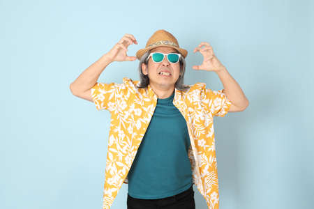 The senior Asian man wearing summer dressed standing on the blue background.の写真素材