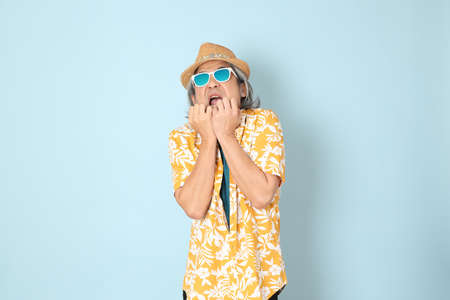 The senior Asian man wearing summer dressed standing on the blue background.