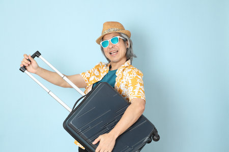 The senior Asian man wearing summer dressed standing on the blue background.の写真素材