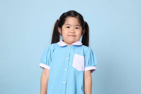 The Asian girl weraing the school uniform standing on the blue background.の写真素材