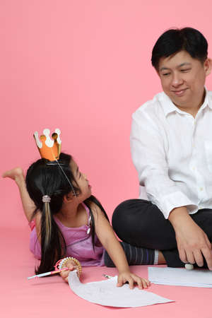 The Asian family sitting on the pink background.の写真素材