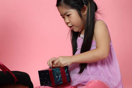 The young Asian girl trying to open the present boxes.