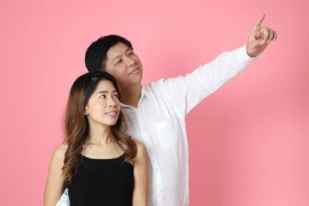The Asian couple standing on the pink background.の写真素材