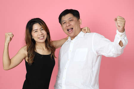 The Asian couple standing on the pink background.の写真素材
