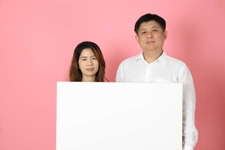 The Asian couple standing on the pink background.の写真素材