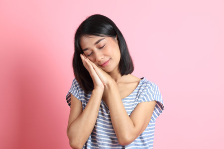 The mixed race woman wearing blue shirt standing on the pink background.の写真素材