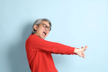 The senior Asian man standing on the blue background.の写真素材