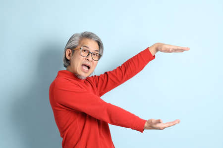 The senior Asian man standing on the blue background.の写真素材