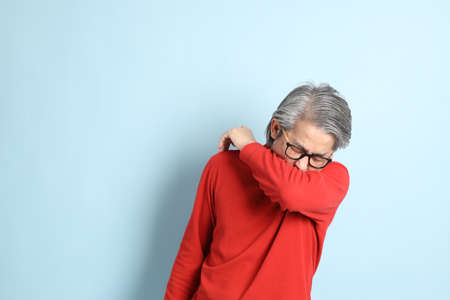 The senior Asian man standing on the blue background.の写真素材