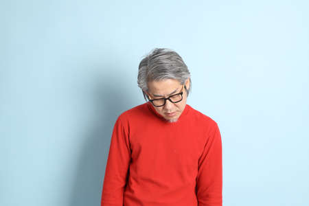 The senior Asian man standing on the blue background.の写真素材