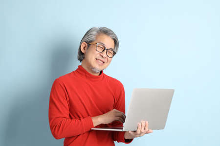 The senior Asian man standing on the blue background.の写真素材