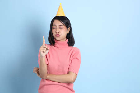 The young Asian woman wearing pink clothes standing on the blue background.の写真素材