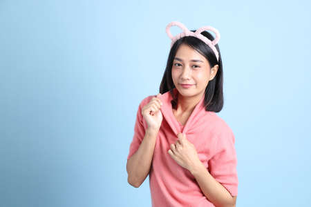 The young Asian woman wearing pink clothes standing on the blue background.の写真素材