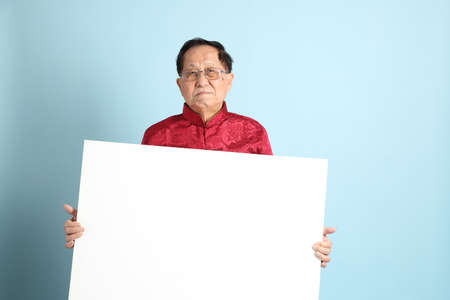 The senior Asian man wearing traditional Chinese shirt on the blue background.の写真素材