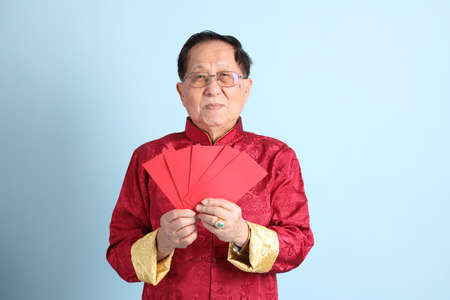 The senior Asian man wearing traditional Chinese shirt on the blue background.