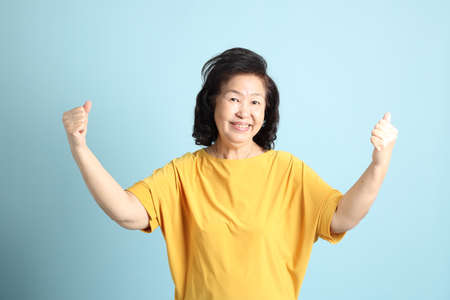 The senior Asian woman on the blue background.