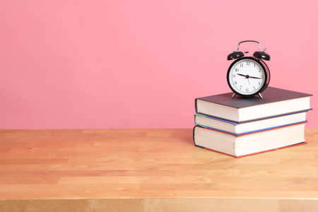 The analog clock setting on the stack of book with color background.の写真素材