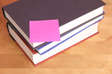 The book stack with pink remind note on the working desk.