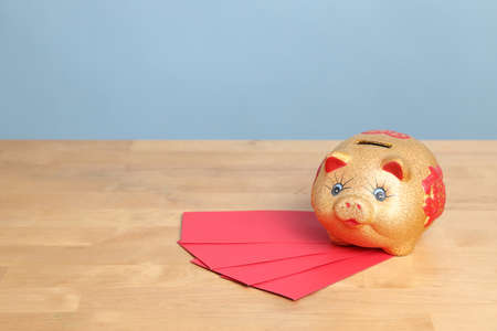 The gold piggy bank setting on the desk with color background.の写真素材