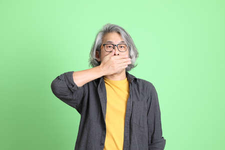 The senior Asian man with smart casual dressed standing against the light green background.の写真素材