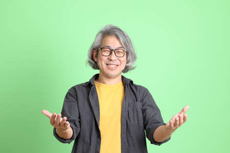 The senior Asian man with smart casual dressed standing against the light green background.の写真素材