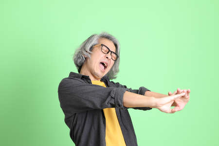 The senior Asian man with smart casual dressed standing against the light green background.の写真素材