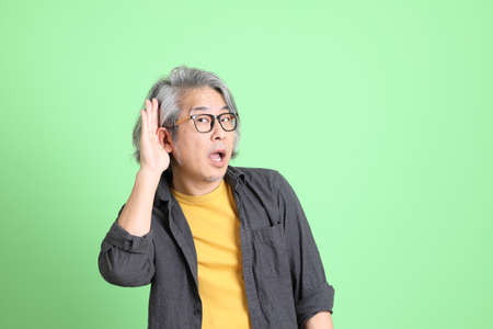 The senior Asian man with smart casual dressed standing against the light green background.の写真素材