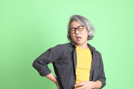 The senior Asian man with smart casual dressed standing against the light green background.の写真素材