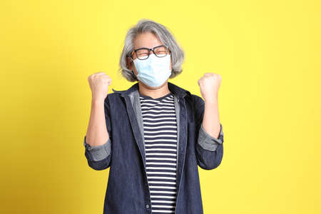 The senior Asian man with jean dressed standing against the yellow background.の写真素材