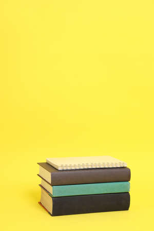The stack of books setting on the yellow background.の写真素材