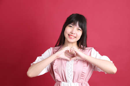 The teen Asian girl with cute Japanese costume standing on the red background.の写真素材
