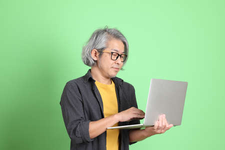 The senior Asian man with smart casual dressed standing against the light green background.の写真素材