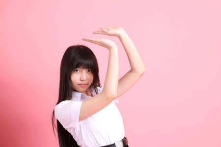The teen Asian girl with university uniform standing on the pink background.の写真素材
