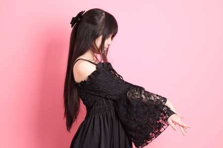 The cute young Asian girl with gothic dressed standing on the pink background