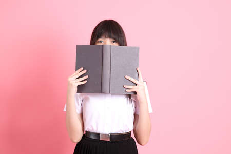 The teen Asian girl with university uniform standing on the pink background.の写真素材