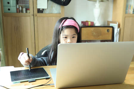 The cute young girl sitting at the desk with laptop.