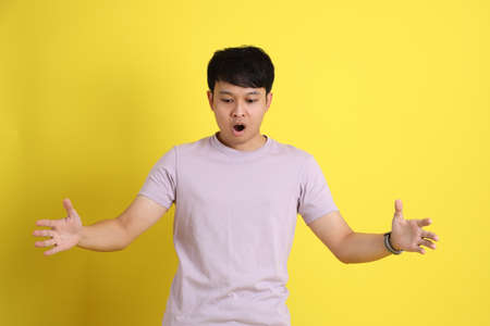 The young adult Asian man standing on the yellow background.の写真素材