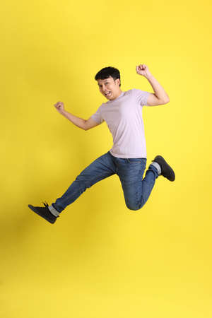 The young adult Asian man standing on the yellow background.の写真素材