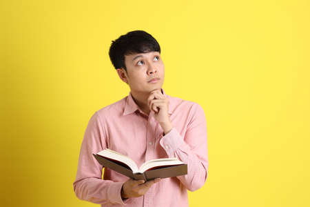The young adult Asian man standing on the yellow background.の写真素材
