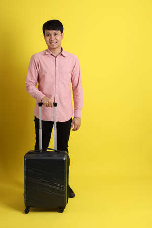 The young adult Asian man standing on the yellow background.の写真素材