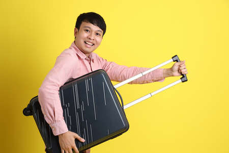 The young adult Asian man standing on the yellow background.の写真素材
