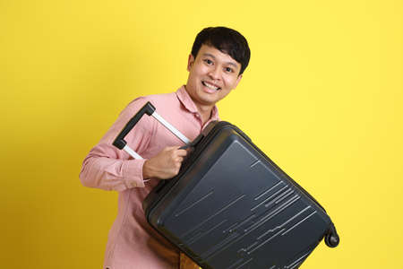 The young adult Asian man standing on the yellow background.の写真素材