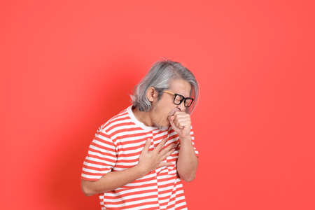 The senior Asian man with casual clothes standing on the orange background.の写真素材