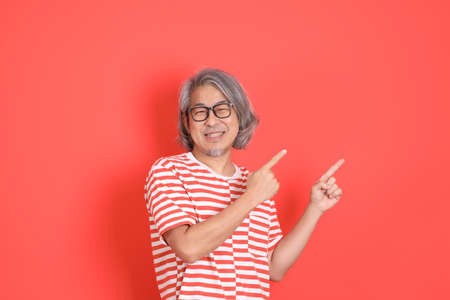 The senior Asian man with casual clothes standing on the orange background.の写真素材